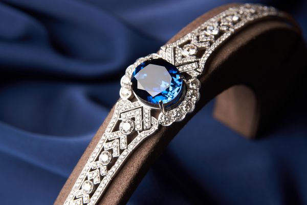 نزدیک دستبند پلاتین زیبا دستبند زنانه لوکس با الماس و یاقوت کبود در پس زمینه آبی ابریشم نزدیک