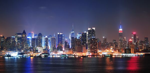در شهر نیویورک شهر منهتن افق مرزی در شب با آسمان خراش ها در بالای رودخانه هادسون با بازتاب ها روشن شده است