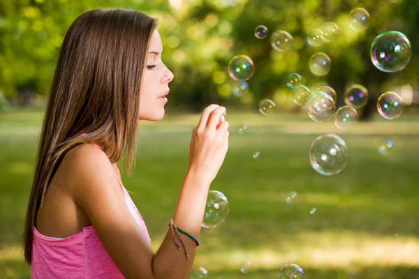 حباب ها را آزاد کنید پرتره از یک دختر زیبا و زیبا سرگرم کننده در خارج از منزل حباب های صابون