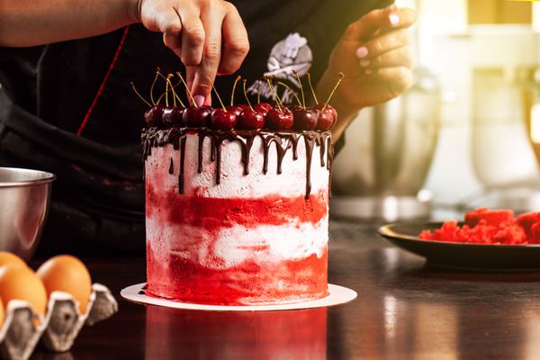 شیرینی ساز آشپز دختر ساخت یک کیک روغن با یک گیلاس فرآیند تولید مفهوم در کیک خانگی به سفارش مشتریان اسپاد کیک کیک کرم دار تصویر پس زمینه