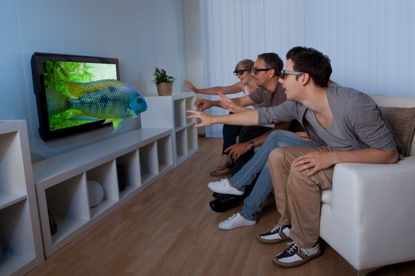تصویر مفهومی خانواده ای که تلویزیون 3D را تماشا می کند و کشیدن دست هایش را مانند تصویر لمس روی صفحه نمایش می دهد