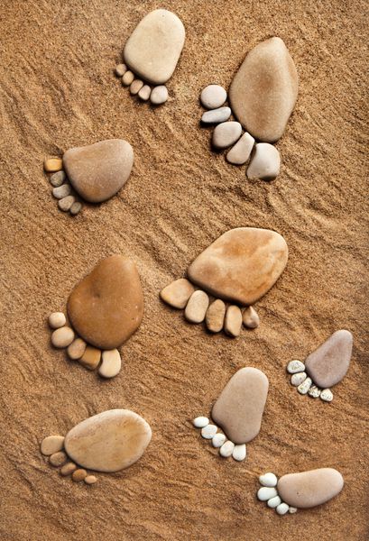 پیاده روی پا برافروخته از سنگ های سنگی در پس زمینه شن و ماسه ساحل