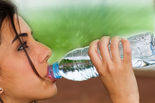 پس از انجام برخی ورزش ها برای سلامتی خوب و سلامت عمومی دختر جوان از یک بطری آب آشامیدنی بخورید