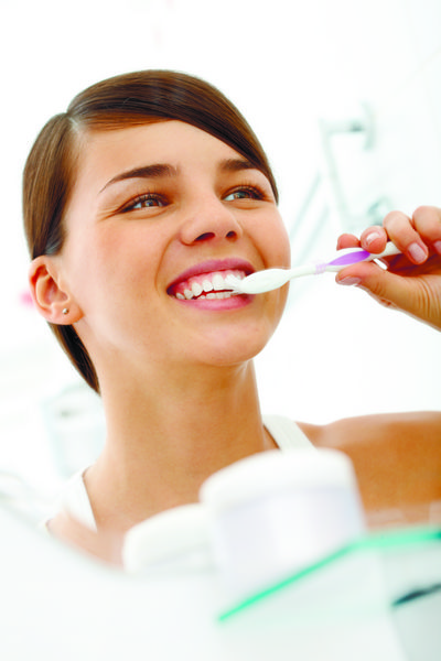 تصویر زیبا زن مسواک زدن دندان هایش را در مقابل آینه در صبح