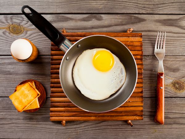 تخم مرغ سرخ شده روی میز چوبی صبحانه