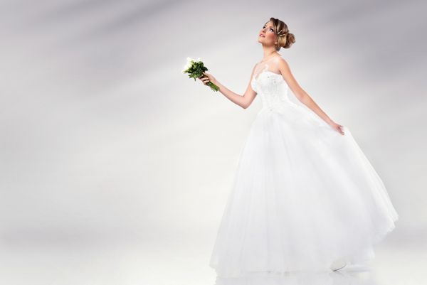 عروس جوان زیبا پوشیدن لباس عروسی برگزاری گل های سفید