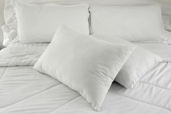 بالش های سفید بر روی تخت بالش راحت نرم بر روی تخت