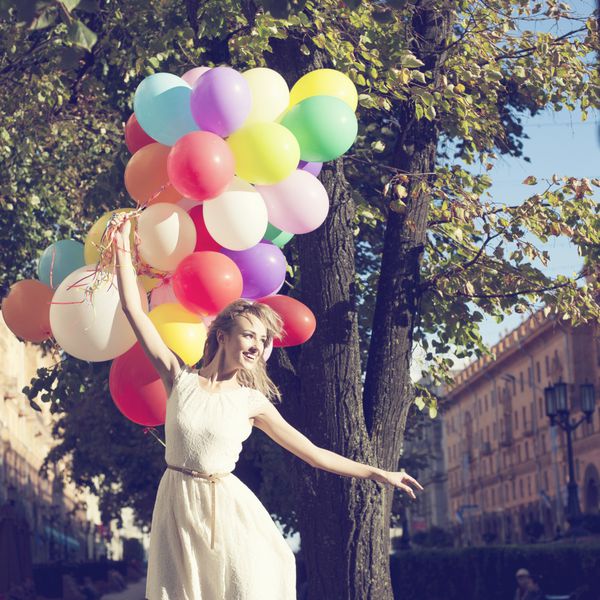 زن جوان مبارک با بالن های رنگی لاتکس در فضای باز