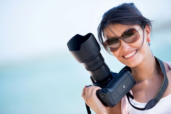 عکاس زن حرفه ای دوربین دار و لبخند میزند