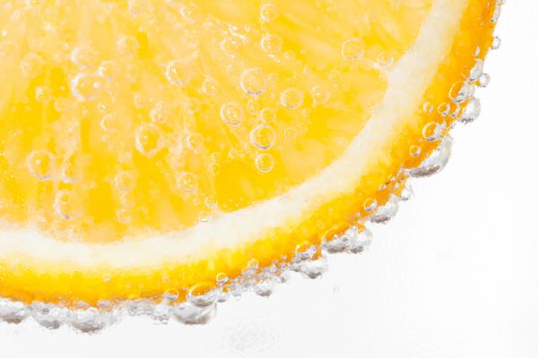قطره پرتقال در آب با حباب جدا شده بر روی سفید