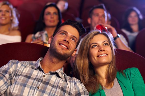 زن جوان مبارک فیلم را در سینما تماشا می کند لبخند می زند