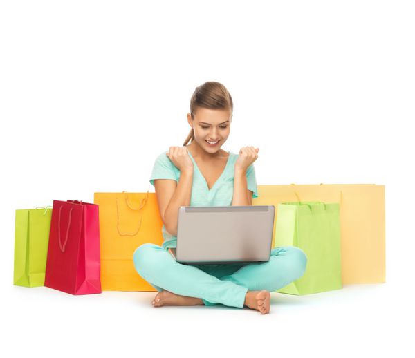 زن جوان با لپ تاپ و کیسه های خرید