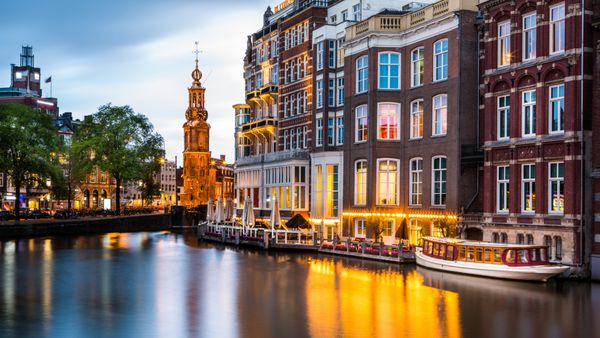 AMSTERDAM THE NETHERLANDS 7 اوت خانه های اصلی هلندی در کانال در غروب خورشید در 7 اوت 2013 در آمستردام هلند منعکس شده است برجسته برج نردبان در پس زمینه قابل مشاهده است