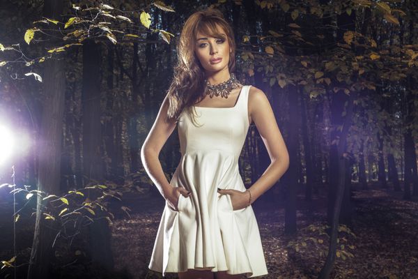 زن زیبای مد زیبا در لباس سفید در جنگل