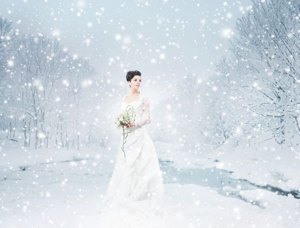 عروس جوان و زیبای با دسته گل در جنگل زمستانی