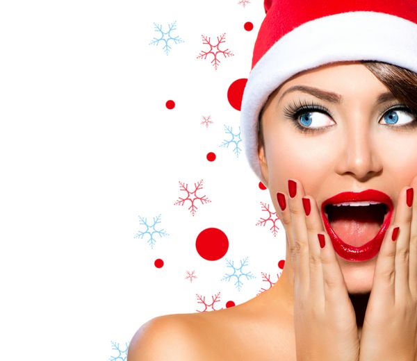 زن کریسمس مدل دختر زیبایی در سانتا کلاه جدا شده بر روی زمینه سفید خنده دار خنده زن پرتره تعجب آور دهان باز احساسات واقعی لب قرمز و مانیکور زیبایی آرایش تعطیلات