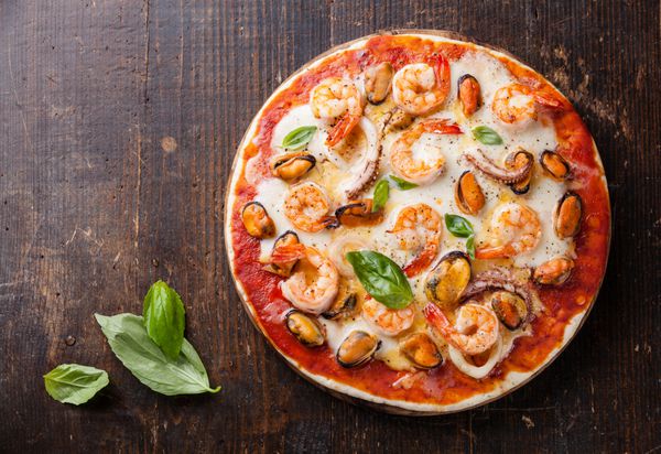 پیتزا ایتالیایی غذای دریایی بر روی میز چوبی