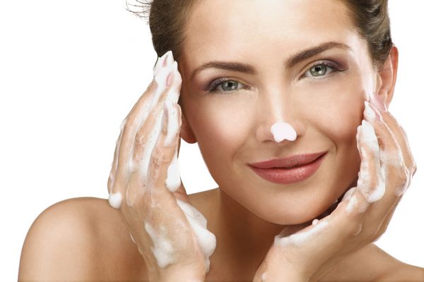 زن زیبا تمیز کردن صورت خود را با درمان فوم در سفید