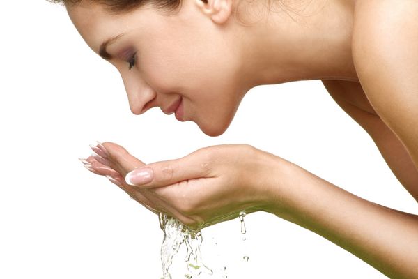 زن زیبا پوست خود را تمیز با آب بر روی سفید