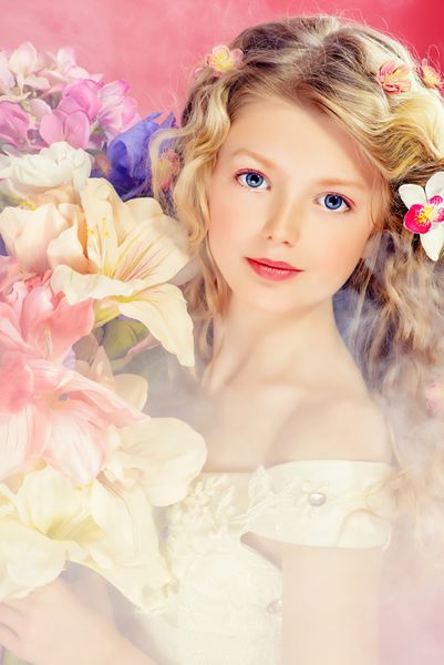 دختر جوان زیبا در لباس عروسی سفید گل دسته گل را نگه می دارد بیش از پس زمینه صورتی