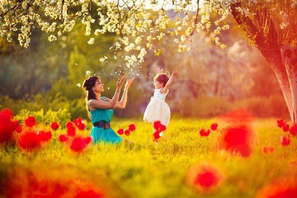 زن مبارک و کودک در باغ سبز شکوفه مفهوم تعطیلات روز مادران