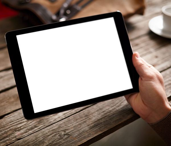 قرص کامپیوتر دیجیتال با صفحه نمایش جدا شده در دست مردانه بیش از پس زمینه کافی نت میز فنجان قهوه