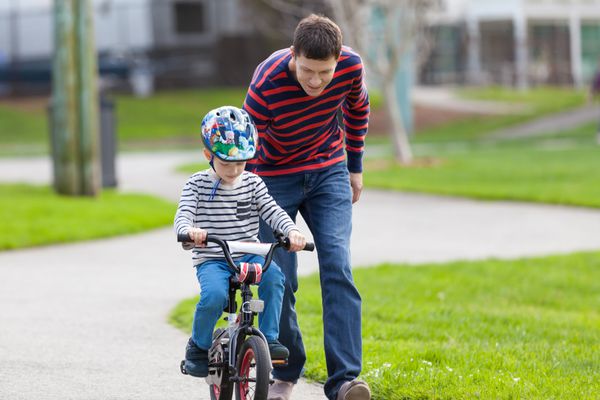 پدر جوان خوش تیپ پسر خود را آموزش می دهد تا دوچرخه سواری کند