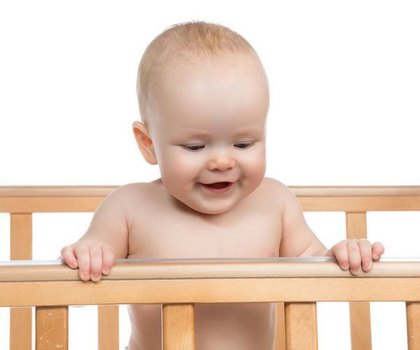 کودک نوزاد نوزاد در تخت چوبی به دنبال پس زمینه سفید