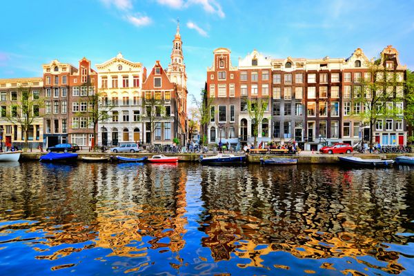 خانه های کانال آمستردام در غروب خورشید با بازتاب های پر جنب و جوش هلند