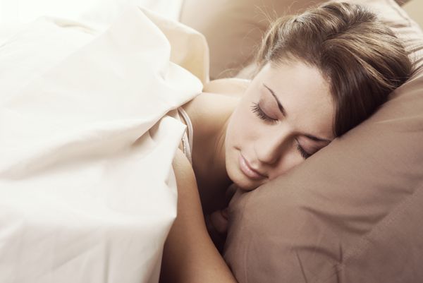 زن زیبا جوان آرام در رختخواب خوابید