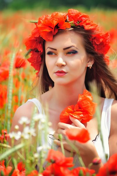 زن جوان زیبا در زمینه خشخاش قرمز روشن پرتره تابستانی