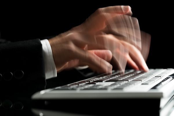 نزدیک شدن دست مردان نازک تایپ بر روی صفحه کلید کامپیوتر بیش از پس زمینه سیاه و سفید