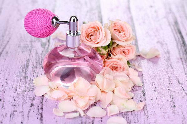 عطر بطری با گلبرگ در جدول نزدیک