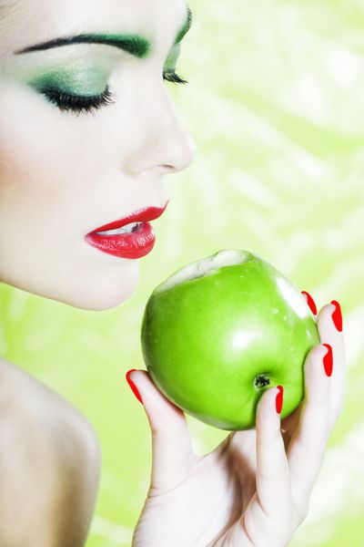 پرتره زن زیبا با آرایش رنگارنگ و پس زمینه نگه داشتن سیب