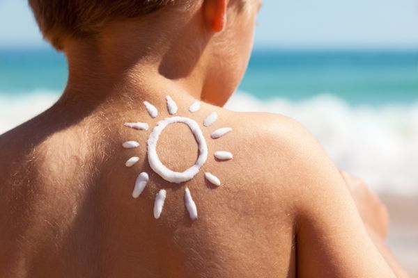کودک با لوسیون غرغرو به عنوان یک خورشید در پشت خود را در مفهوم ساحل برای حفاظت از خورشید و مراقبت از پوست برای کودکان شکل گرفته است