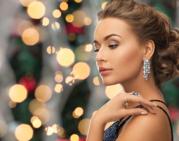 مردم تعطیلات و مفهوم زرق و برق زن زیبا در لباس عروسی پوشیدن حلقه و گوشواره بیش از پس زمینه کریسمس چراغ