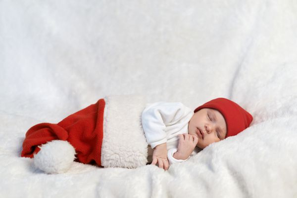 نوزاد زیبا در کلاه سانتا در حال خواب است