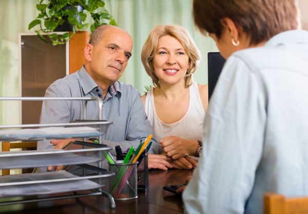 زن و شوهر بالغ از بازنشستگان با کارمند در دفتر صحبت می کنند