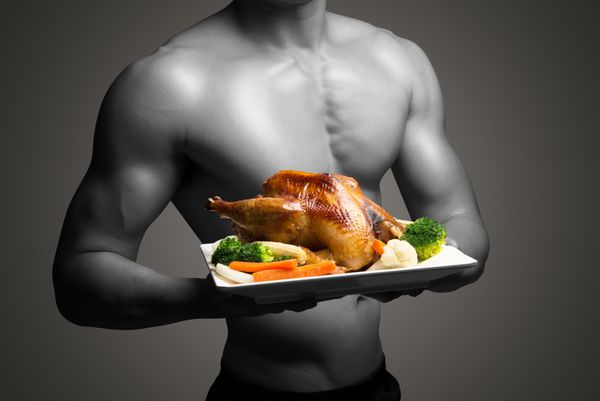 مرد جوان با بدن کامل نگه داشتن و نمایش مرغ سرخ شده برای منوی خوشمزه غذای سالم مفهوم زندگی سالم