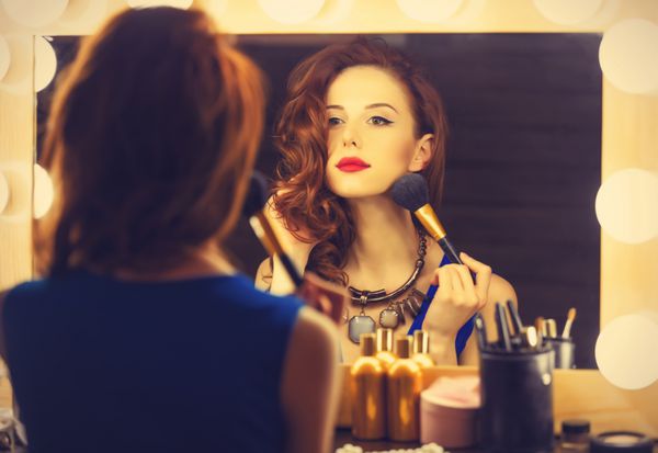 پرتره یک زن زیبا به عنوان استفاده از آرایش در نزدیکی آینه عکس در سبک رنگی یکپارچهسازی با سیستمعامل