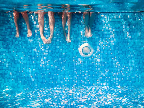 کودکان و بزرگسالان پاها زیر آب در استخر شنا