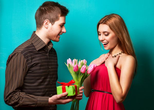 پرتره از زن و شوهر جوان در عشق نما در استودیو لباس در لباس های کلاسیک این پسر گل و هدیه مفهوم روز ولنتاین را می دهد