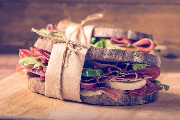 دو ساندویچ با بیکن و سبزیجات تازه بر روی تخته خرده چوب بر روی چوب در سبک instagram filter نزدیک