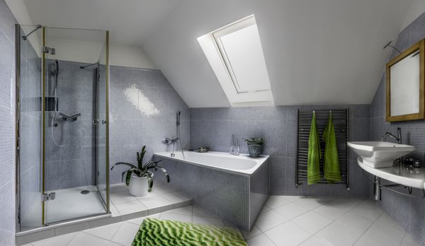 حمام مدرن در سبک سرد با دوش شیشه ای و وان حمام در اتاق زیر شیروانی یک خانه
