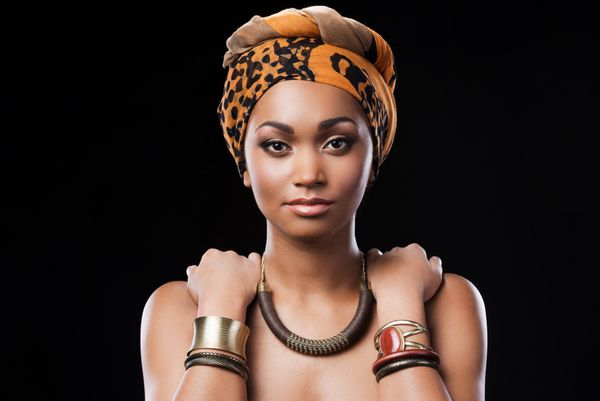 ملکه آفریقایی زن زیبا آفریقایی پوشیدن روسری و لمس شانه های خود را در حالی که ایستاده در مقابل زمینه سیاه و سفید