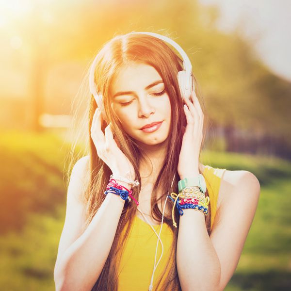 زن جوان قفقازی با هدفون در فضای باز در تابستان آفتابی دختر نوجوان ساله گوش دادن به موسیقی پوشیدن پیراهن زرد و جواهرات پر جنب و جوش قالب مربع retouched فیلتر