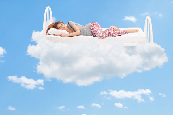 زن جوان آرامشبخش خوابیدن روی یک تخت راحت در ابرها