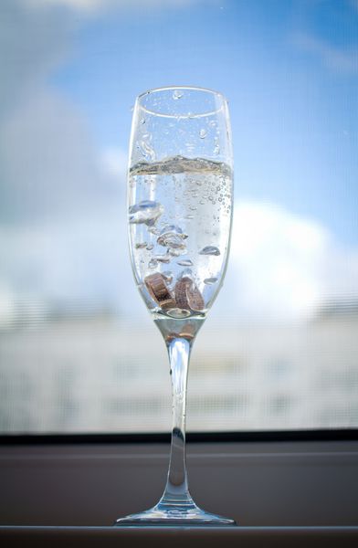 حلقه های عروسی در شیشه ای با شامپاین روی یک پنجره