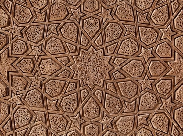 الگوی اسلامی گل و ستاره حک شده در سطح یک درب چوبی قدیمی است