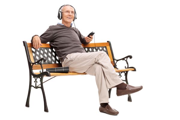 نشسته لذت بخش نشسته بر روی نیمکت چوبی و گوش دادن به موسیقی در تلفن همراه خود را جدا شده بر روی زمینه سفید